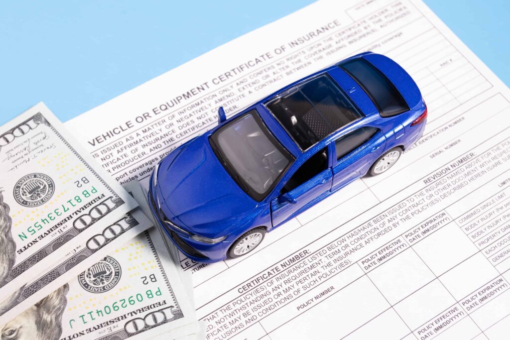 Toy car placed on a vehicle insurance certificate with U.S. dollar bills, representing auto insurance coverage, claims, and financial compensation.