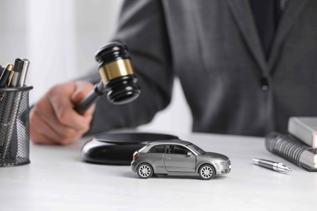 Judge holding a gavel above a toy car on a desk, symbolizing auto accident litigation, insurance claims, and vehicle liability law.